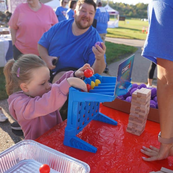 young girl plays a connect-four-style carnival game
