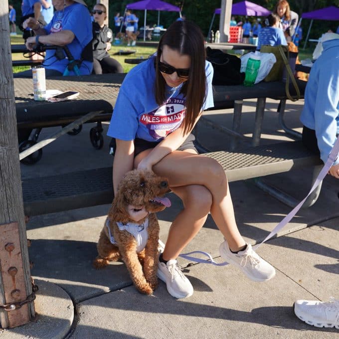 Girl on bench pets her dog