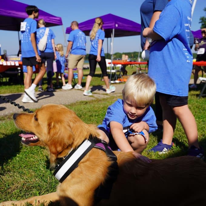 Young boy leans over to pet panting golden retriever